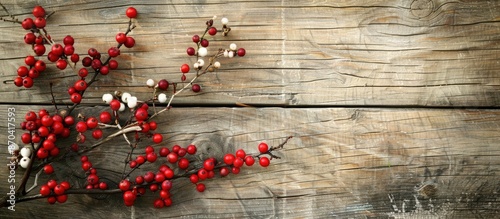 A vintage wooden background with a twig of red and white christmas berries offers a serene setting for a copy space image.