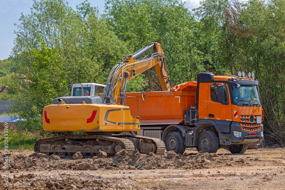 Tipper Truck Loading With Dirt With Excavator Machinery at Construction Site Tipper Truck Loading With Dirt With Excavator Machinery at Construction Site