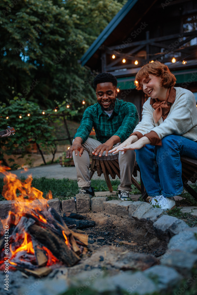 Two people warming their hands by a backyard camping fire Two people warming their hands by a backyard camping fire