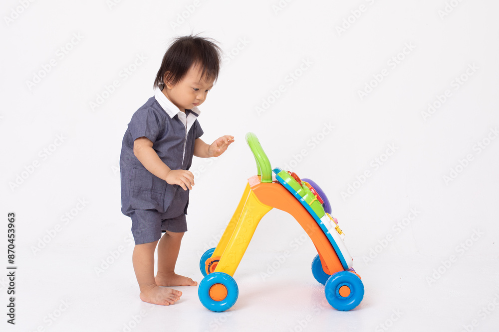 curious Asian toddler wearing a blue outfit with white collar playing with colorful push walker toy. The child focused on exploring the toy showcasing an early learning and development moment curious Asian toddler wearing a blue outfit with white collar playing with colorful push walker toy. The child focused on exploring the toy showcasing an early learning and development moment