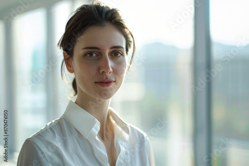 Portrait of a young woman in a white shirt looking at the camera. © SunPunjiStudio
