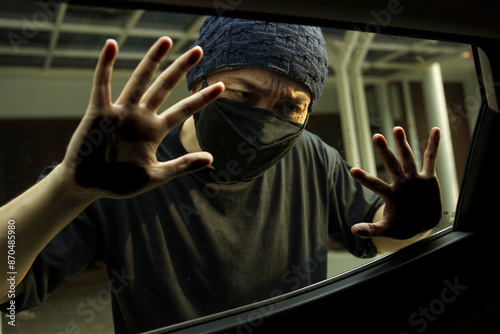 Fotografía Man In Black Mask Looking Through Car Window And Wondering How To Break Into The Car