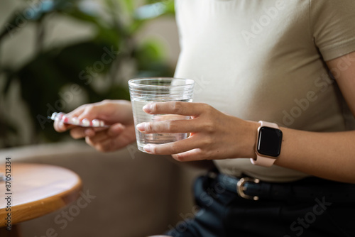 Woman Holding Pills and a Glass of Water for Healthcare and Medication Concept