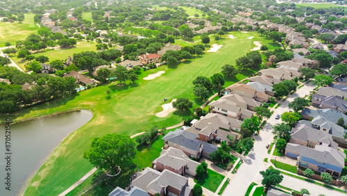 Upscale golf community in master planned subdivision urban sprawl, grassy fairway, sand trap bunkers, golfer playing with expensive new development two story mansion houses, Plano Texas, aerial photo