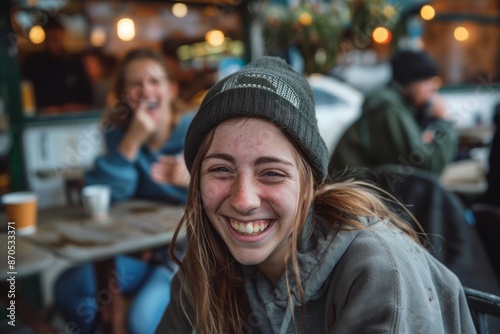 A person with natural unedited skin smiling and laughing while spending time with friends in an outdoor cafe capturing the joy and authenticity of the moment © DK_2020