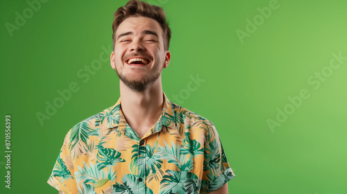 A joyful millennial man wearing a casual shirt, posing with a confident smile against a solid green background