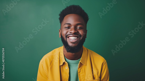 A joyful millennial man with a confident smile, posing against a solid green background