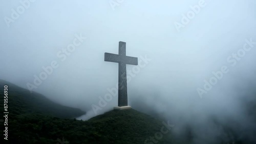 Religious cross on a mountain in a foggy landscape. Silhouette of cross on mountain moody fog mystery dark