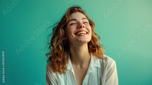 A joyful millennial woman in white, confidently smiling against a solid turquoise background