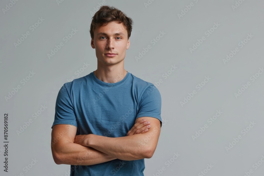 Young man in blue shirt standing with crossed arms