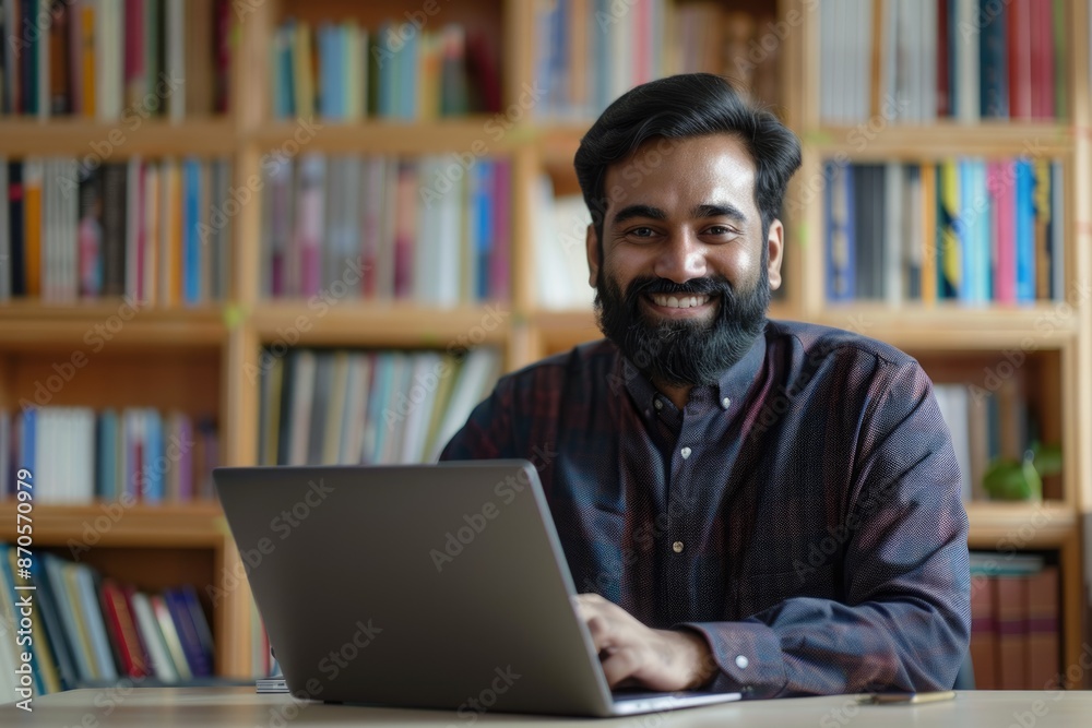 Indian man working and studying remotely on laptop at home.