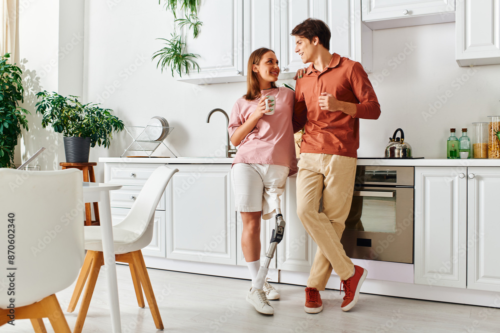 A woman with a prosthetic leg and her boyfriend enjoy a casual moment together in their kitchen. A woman with a prosthetic leg and her boyfriend enjoy a casual moment together in their kitchen.