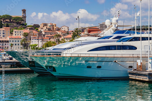 Luxury yachts are peacefully anchored in a beautiful Mediterranean harbor with picturesque views. Old city and harbor in Cannes, French Riviera, France.