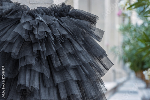 Black layered tutu laying on the stone stairs. Tulle ballerina skirt. Multilayered black skirt. Closeup. Selective focus
