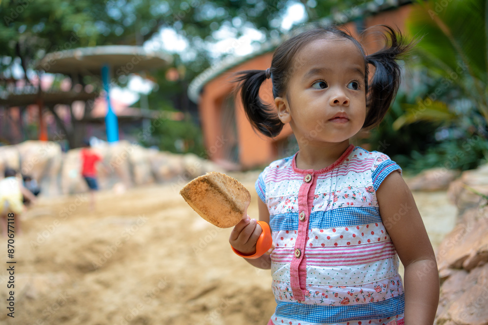 Asian kindergarten boy and girl enjoy playing in sandbox having fun on playground in sandpit.