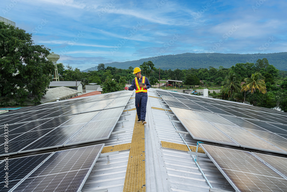 Naklejka premium A diligent engineer performs a detailed inspection of solar panels on a rooftop, surrounded by a mountains.