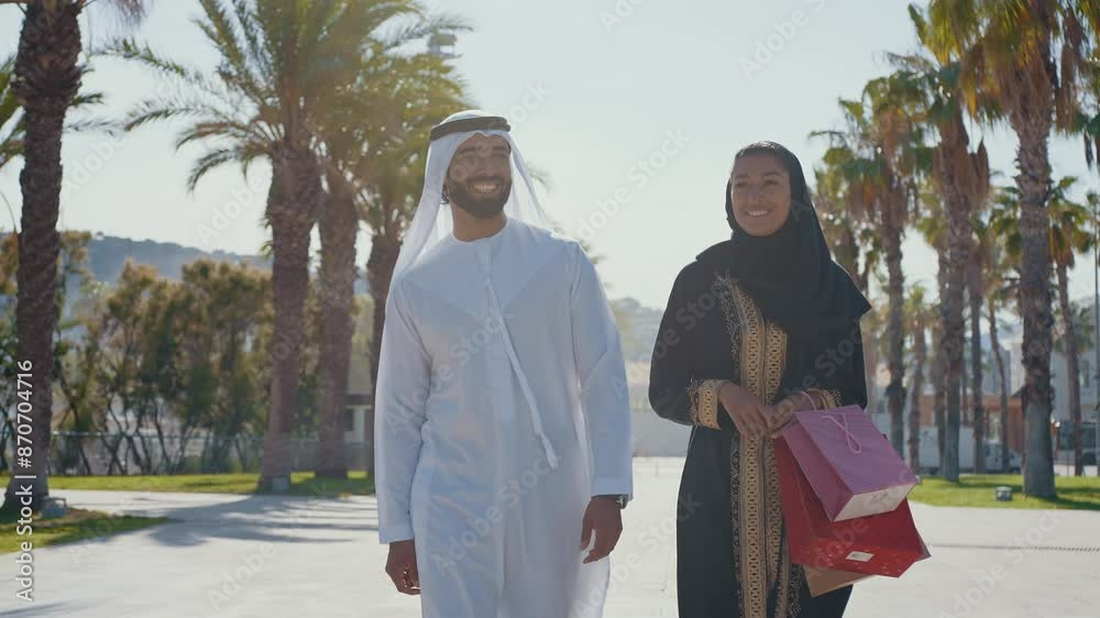 Cinematic image of a young couple from the united arab emirates spending time outdoor. Man and woman with traditional emirati kandura and abaya in Dubai.