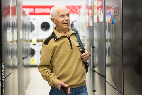 Senor man pensioner buying fridge in showroom of electrical appliance store © caftor