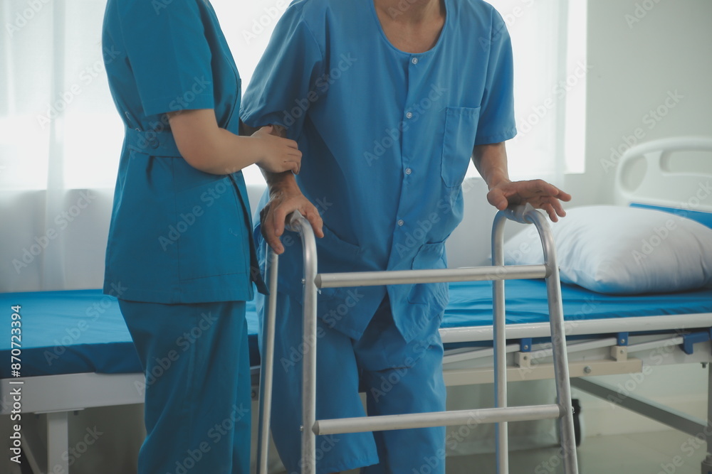 Physical therapist helps a male patient use a walker to practice walking. Support yourself from recovery from sore legs and ankles. Physical therapy service concept. Physical therapist helps a male patient use a walker to practice walking. Support yourself from recovery from sore legs and ankles. Physical therapy service concept.