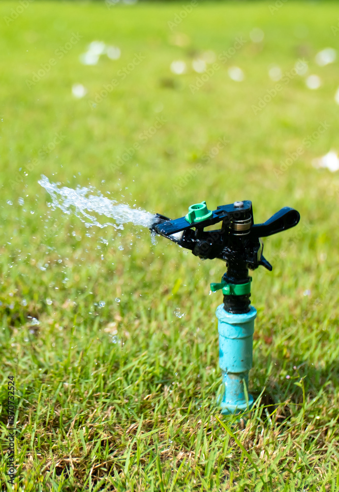 Sprinkler for automatic lawn watering. Lawn cultivation and care, garden irrigation devices. Rainbow over the garden on a sunny day. Sprinkler for automatic lawn watering. Lawn cultivation and care, garden irrigation devices. Rainbow over the garden on a sunny day.