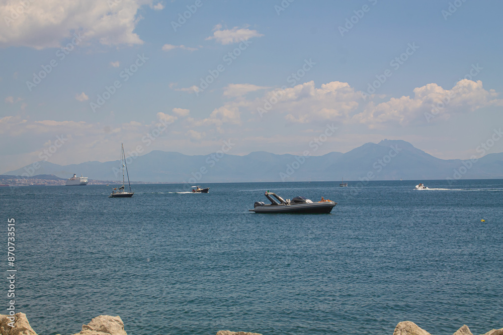 Obraz premium Sailing boat on the blue sea on the background of mountains and Mount Visuvius in the Bay of Naples, southern Italy. Yachts on the coast