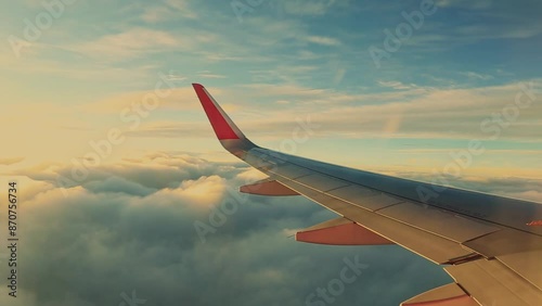 big airplane wing window view flying above the clouds at sunset golden hour view from window
