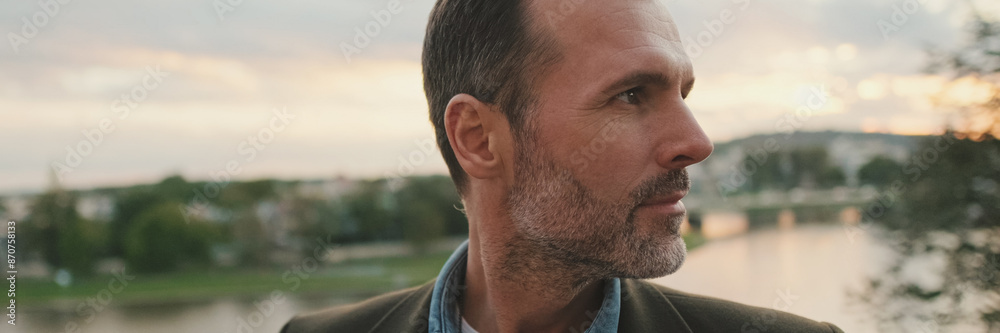 Fototapeta premium Man looks around standing against the background of the river, panorama