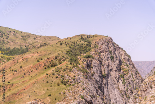 A mountain with a rocky cliff and a green hillside