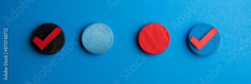 Four Colorful Circles with Checkmarks on Blue Background - Four wooden circles painted in different colors, with red checkmarks on them, are arranged horizontally on a blue background. - Four wooden c photo