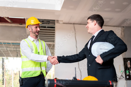 Two men shaking hands, one wearing a yellow vest
