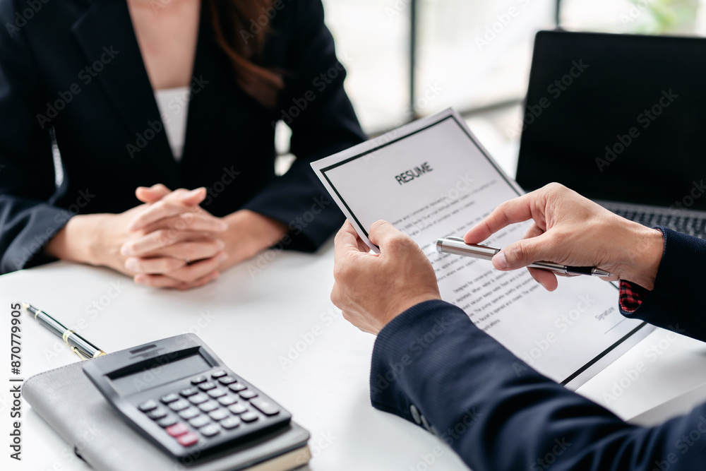 A man and a woman are sitting at a table with a resume in front of them A man and a woman are sitting at a table with a resume in front of them