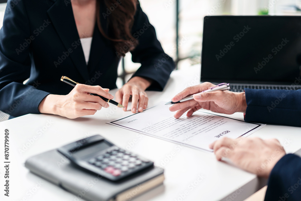 Two people are sitting at a table with a piece of paper in front of them Two people are sitting at a table with a piece of paper in front of them