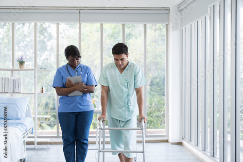 Nurse help patient man walk with walker careful at hospital. Woman assistant caring patient man walking with walker