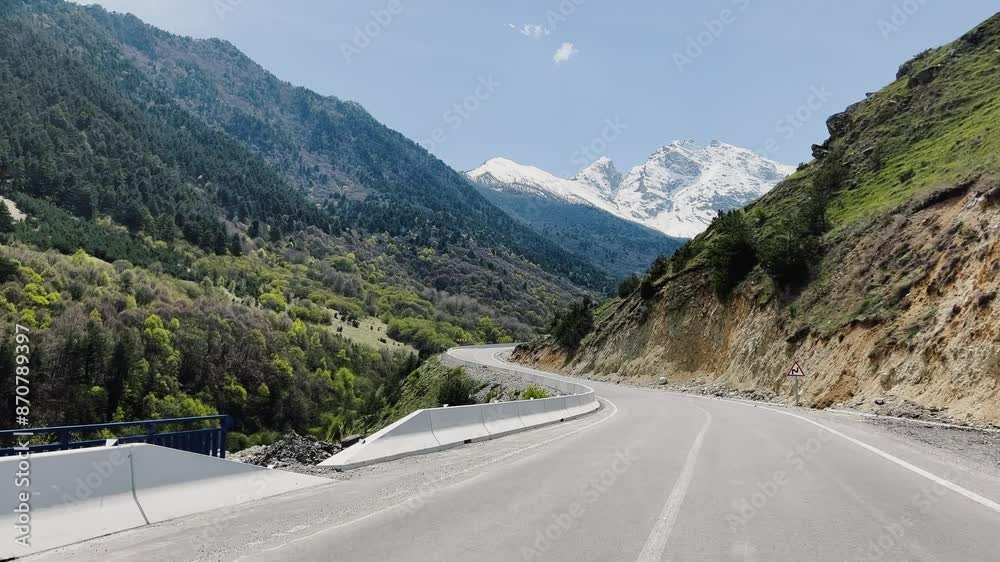 Mountain road winding through highland with trees and clouds in the sky Mountain road winding through highland with trees and clouds in the sky