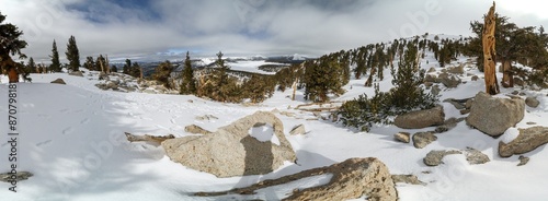 A snowy mountain landscape with a large rock in the foreground