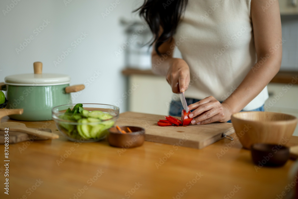 A woman is cutting vegetables on a wooden cutting board A woman is cutting vegetables on a wooden cutting board