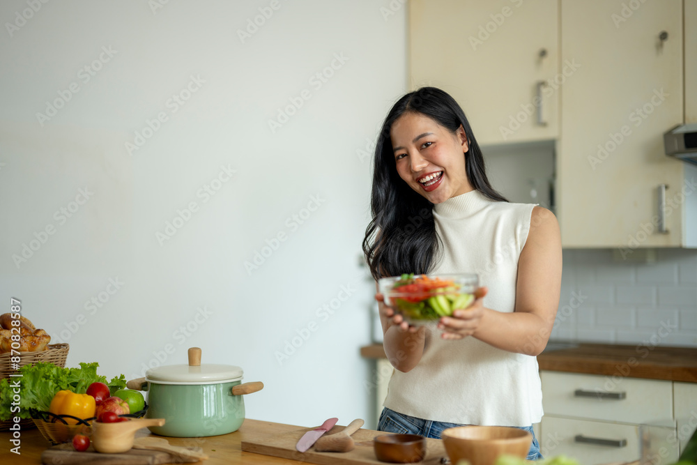 A woman is smiling and holding a bowl of salad in a kitchen A woman is smiling and holding a bowl of salad in a kitchen