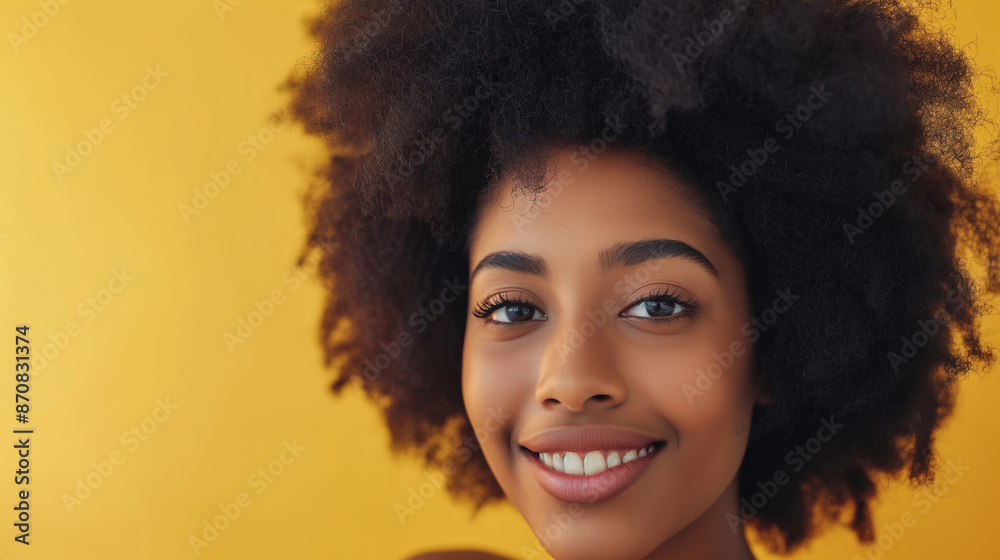 A woman with curly hair is smiling at the camera. She has a bright, happy expression on her face