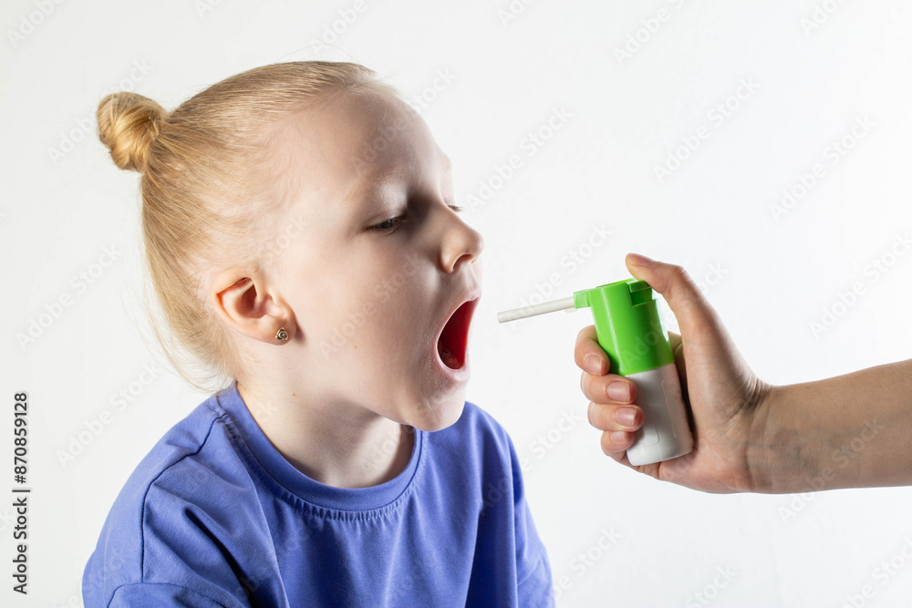 Spraying an antiseptic spray with an antibiotic into the throat of a child for throat diseases and sore throat. Anti-inflammatory and analgesic spray. Treatment of throat diseases, copy space for text Spraying an antiseptic spray with an antibiotic into the throat of a child for throat diseases and sore throat. Anti-inflammatory and analgesic spray. Treatment of throat diseases, copy space for text