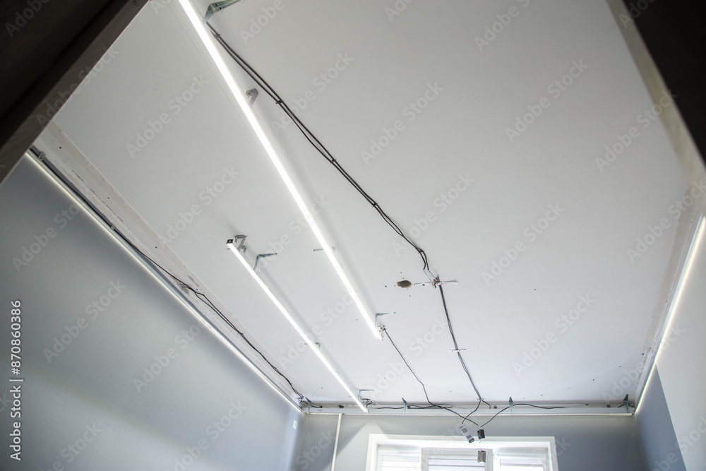Installation of a suspended modern ceiling with LED light lines in an apartment, industry Installation of a suspended modern ceiling with LED light lines in an apartment, industry