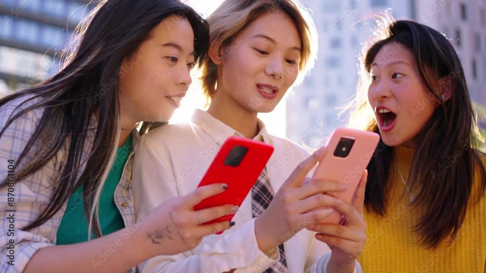 Group of only Chinese generation z women sitting together looking and searching for information on mobile phone outdoors. Young urban Asian girls friends talking using smartphone enjoying sunny day