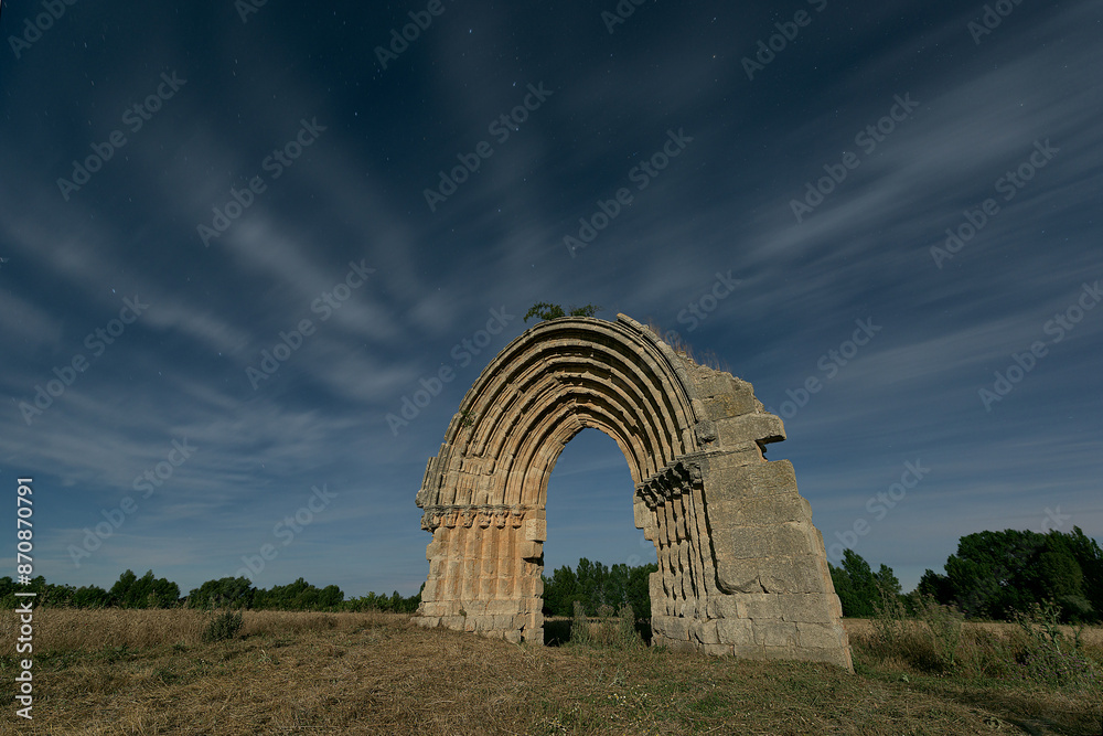 Fototapeta premium Night view of the arch of the missing church of San Miguel de Mazarreros, in Sasamon, Burgos, illuminated by the moonlight