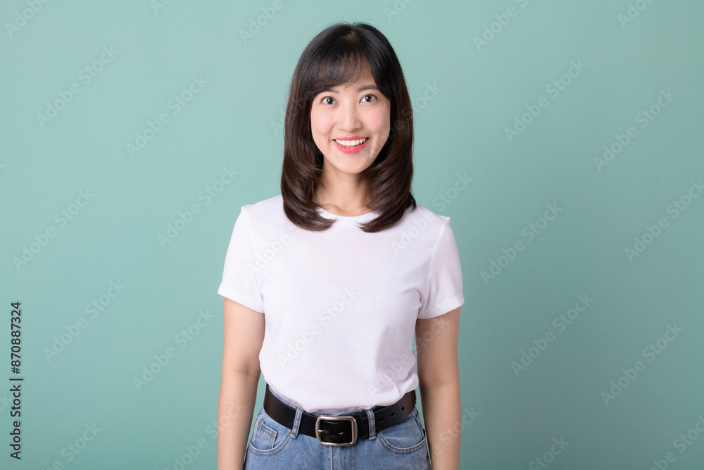 Smiling positive, attractive asian woman in white t-shirt, confident look, green background.