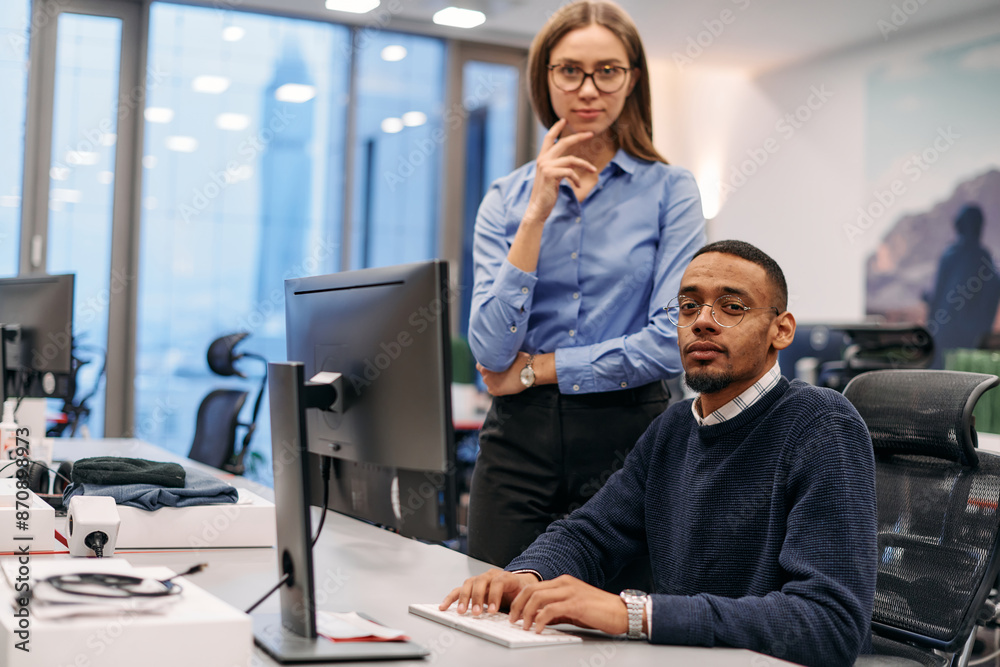 Fototapeta premium Digital Collaboration: Blonde Businesswoman and African American Partner Reviewing Documents Online