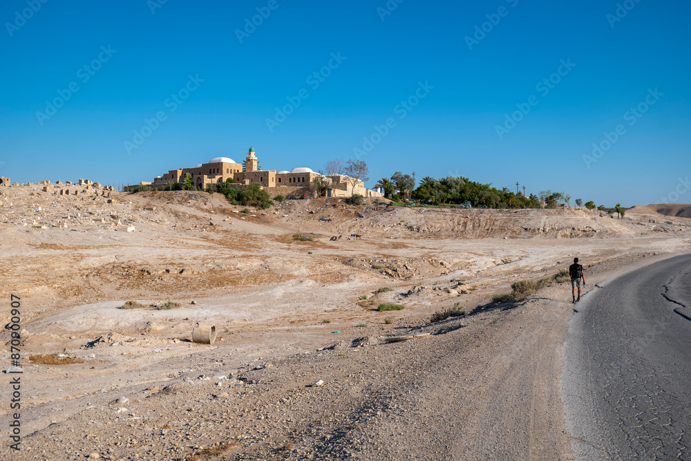 Young Male Explorer Walks Toward An Nabi Musa Mosque and Oasis Garden Seen From Afar