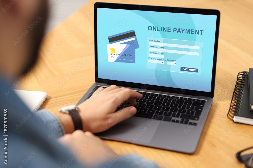 Man using online payment application on laptop at table, closeup Man using online payment application on laptop at table, closeup