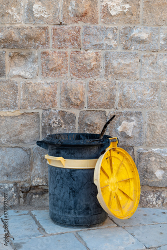 Tail of a Cat Appears Out From a Black and Yellow Plastic Garbage Can
