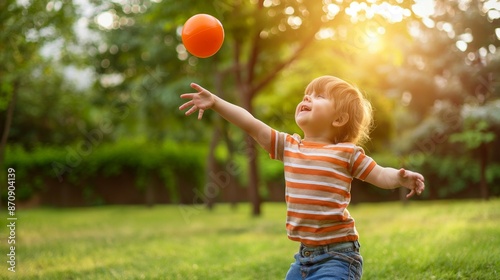 Happy child playing with a ball in a park