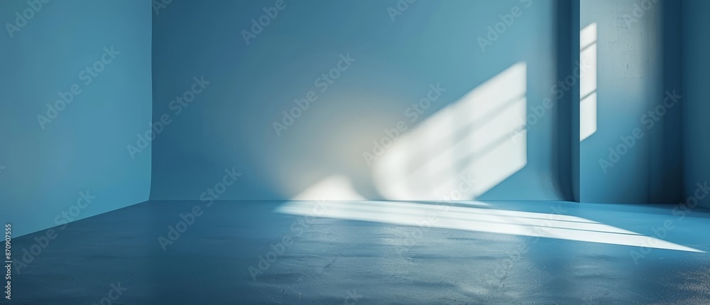 A room devoid of furnishings, featuring a blue-hued wall, and illuminated by a brilliant light filtering in from a window situated on the room's opposite end A room devoid of furnishings, featuring a blue-hued wall, and illuminated by a brilliant light filtering in from a window situated on the room's opposite end