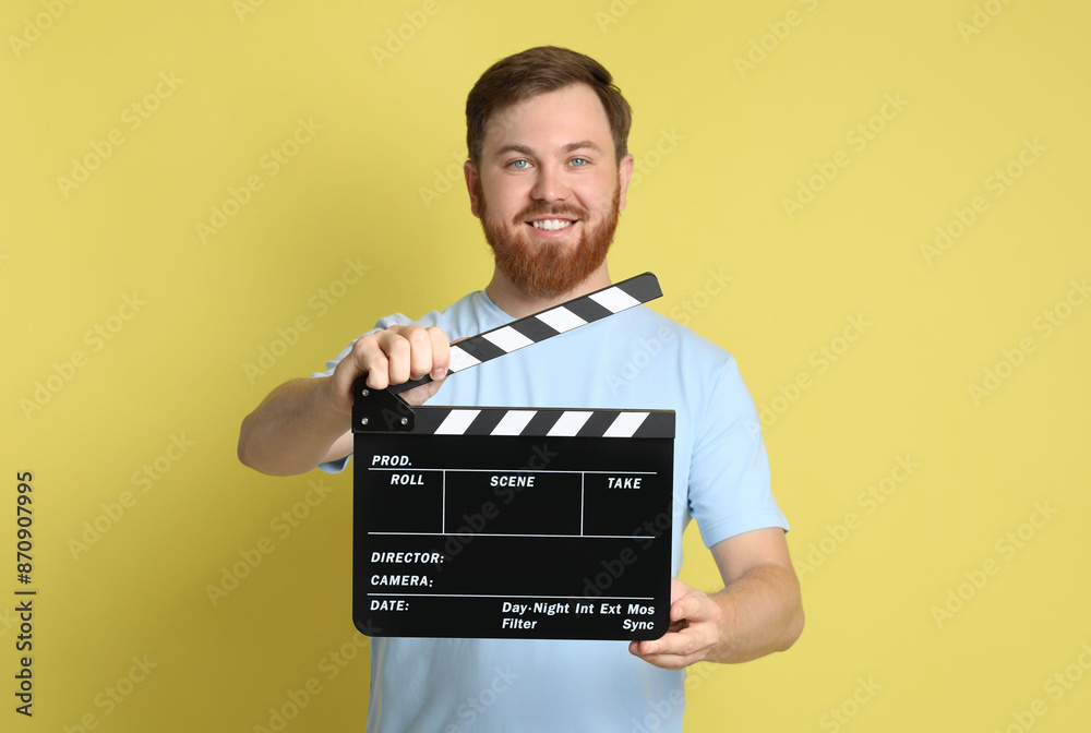 Making movie. Smiling man with clapperboard on yellow background Making movie. Smiling man with clapperboard on yellow background